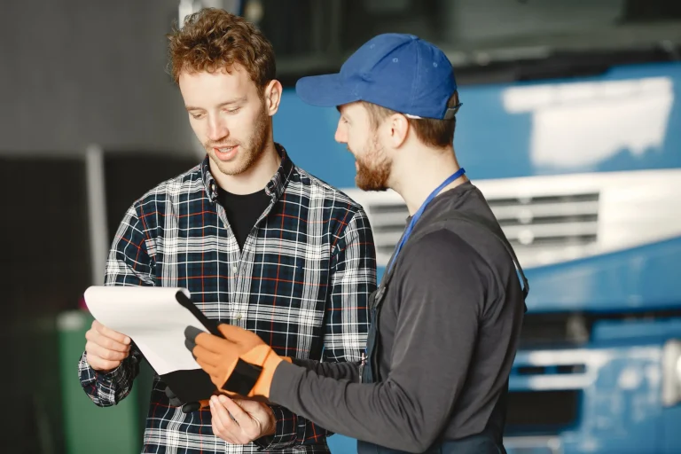 two-guys-talking-about-work-work-garage-near-truck-transfer-documents-with-goods